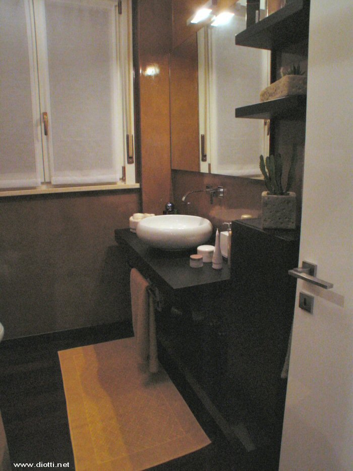 Un'immagine laterale del bagno di servizio: la foto non  bellissima ma d una visione interessante del gioco di profondit fra top superiore porta-lavabo, top inferiore d'appoggio e pensile contenitore.